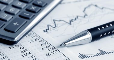 financial graphs with pen and calculator