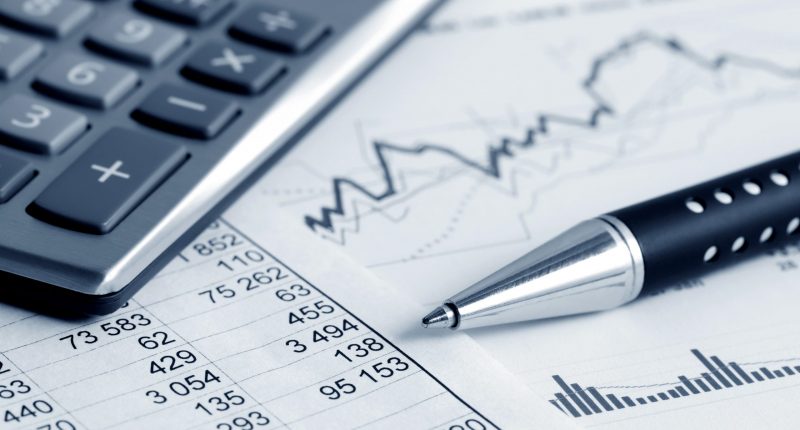 financial graphs with pen and calculator