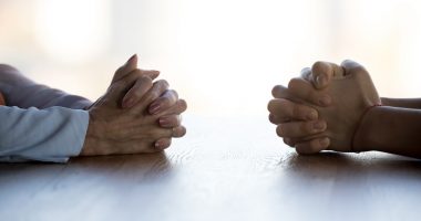 Two people sitting across from each other with their hands folded