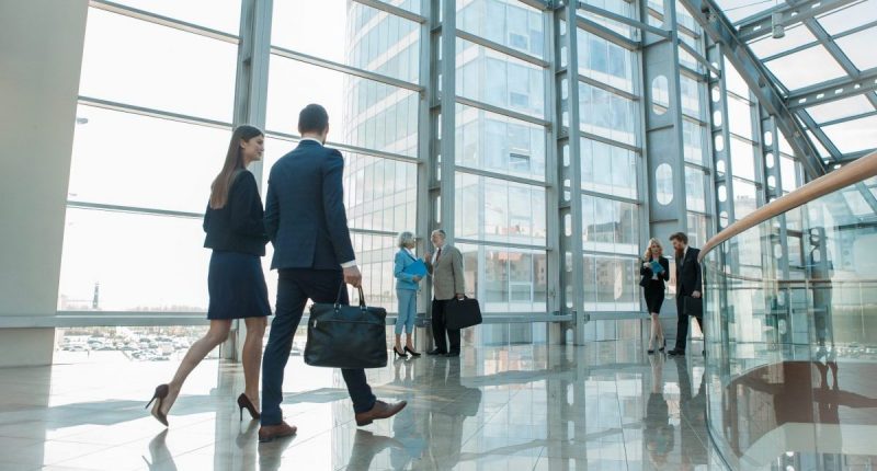 A man and a woman walking down a hallway holding briefcases