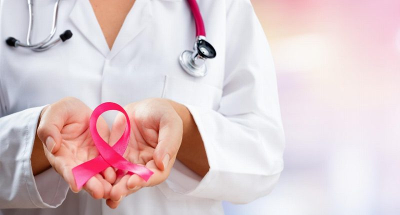 healthcare worker holding pink ribbon representing breast cancer awareness