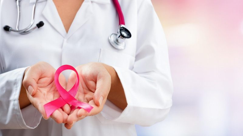 healthcare worker holding pink ribbon representing breast cancer awareness