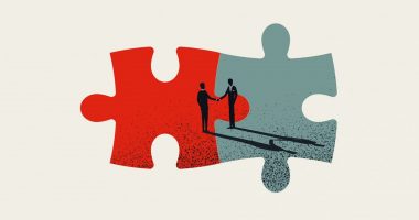 Two pieces of a puzzle fitting together with image of two people shaking hands in background