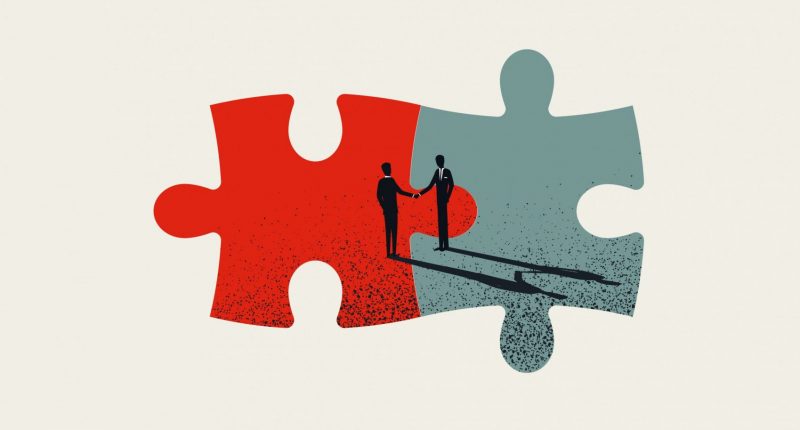 Two pieces of a puzzle fitting together with image of two people shaking hands in background