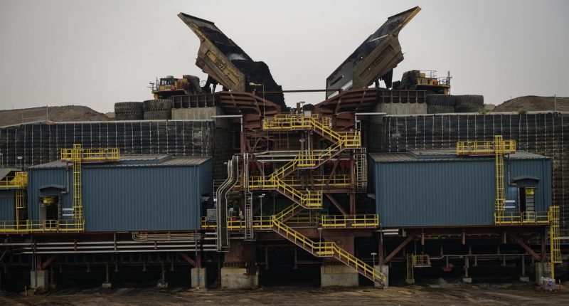 Suncor Energy - Two haul trucks emptying their loads into a crusher at Fort Hills.
