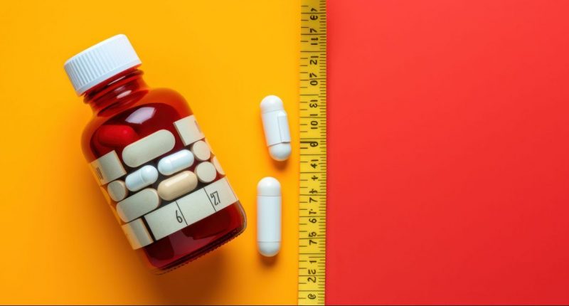 weight loss pills and bottles with stomach circumference measurements