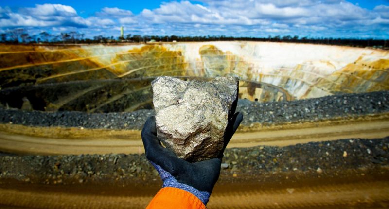 A miner's hand holds nickel ore rock at a Victory Battery Metals Corp. mining pit