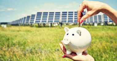 Piggy bank with solar panels in a field in the background