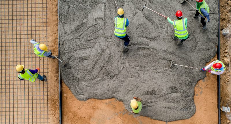 A group of construction workers spreading cement.