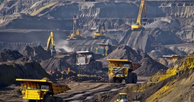 Trucks and excavators at work in an open pit gold mine.