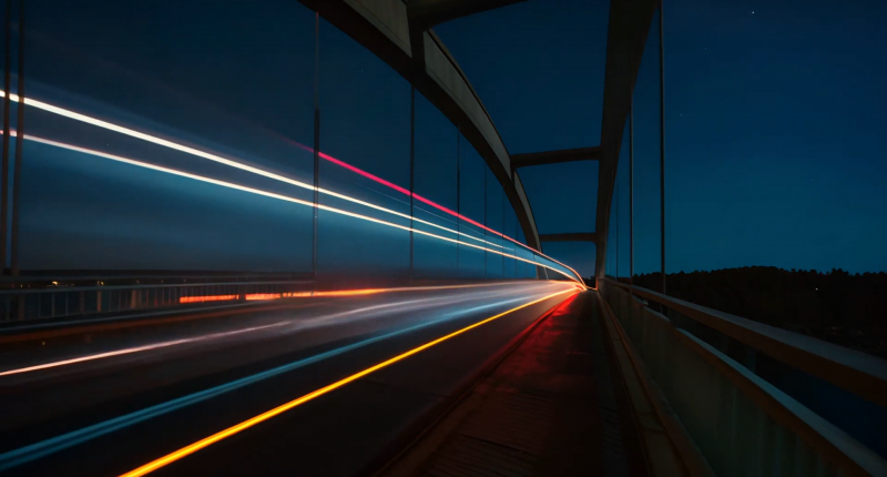 Beams of light traveling across a bridge at night.