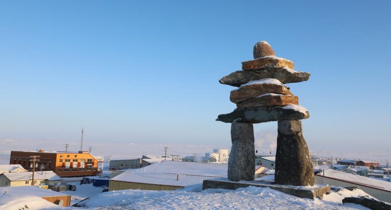 Single Inuksuk or Inukshuk landmark covered in snow on the top of the hill in the community of Rankin Inlet, Nunavut