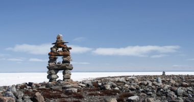 Inuksuk landmark with frozen bay in the background near Arviat, Nunavut