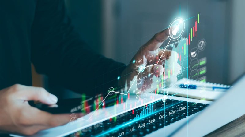 A person uses a laptop to analyze sales data and graph economic growth. 