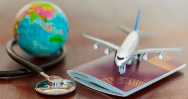 Travel insurance photo illustration of a globe, airliner, passport and stethoscope.