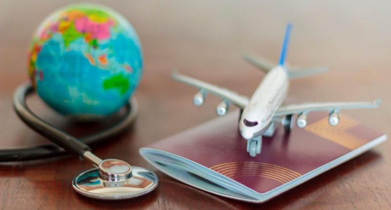 Travel insurance photo illustration of a globe, airliner, passport and stethoscope.