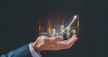 Businessman holding virtual trading graph and blurred coins on hand