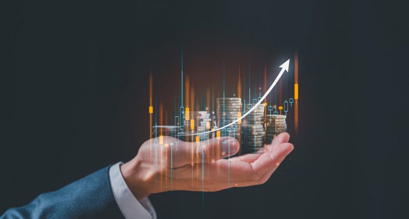 Businessman holding virtual trading graph and blurred coins on hand