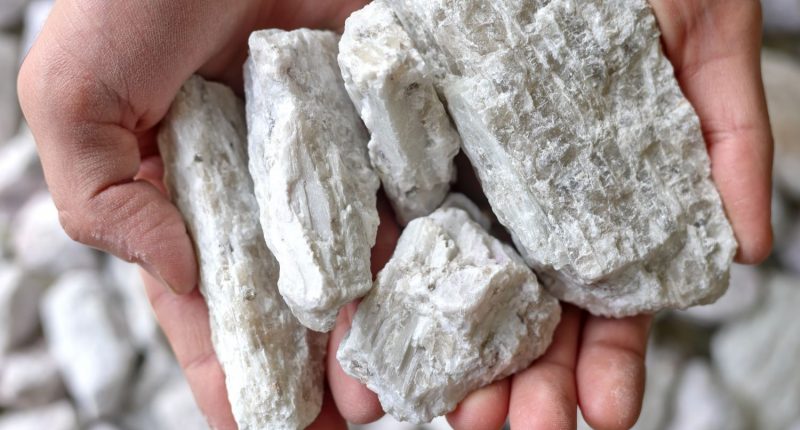 Hands holding hard rock spodumene ore, a commercially important source of lithium.